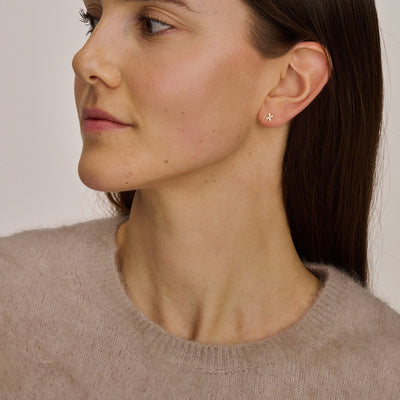 14k goud oorknoppen met zirkonia op oor van vrouw, subtiel en glanzend.