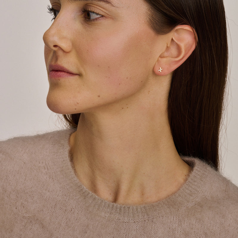 14k goud oorknoppen met zirkonia op oor van vrouw, subtiel en glanzend.