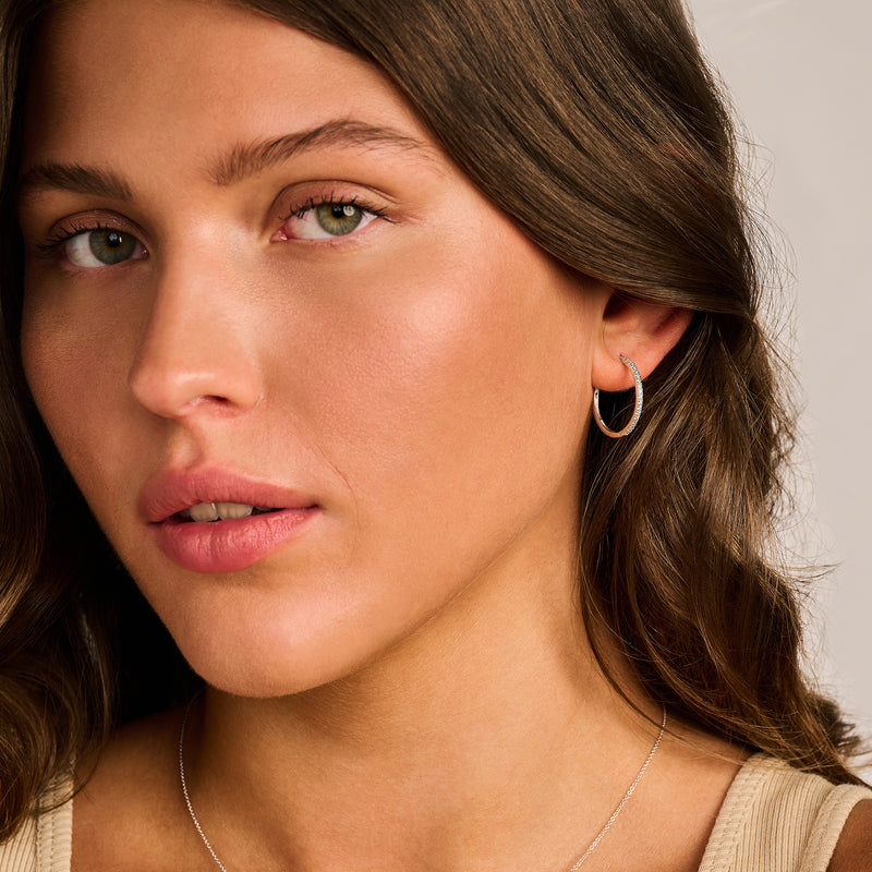 Oorringen van 14k wit goud met kleine zirkonia, subtiel en glanzend aan model.