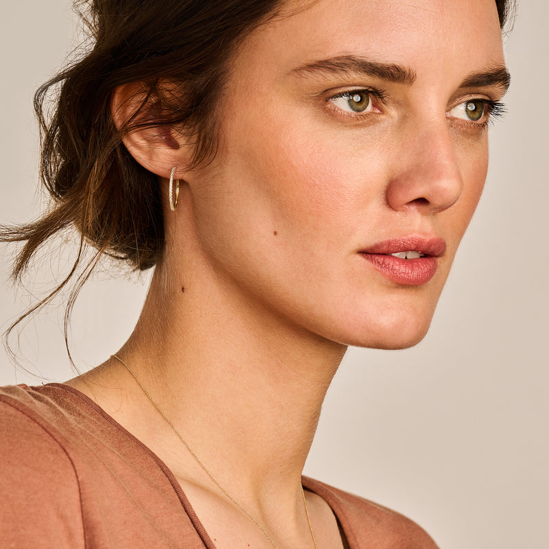 Oorring in 14k geelgoud met kleine zirkonia sluiting zichtbaar aan oor.