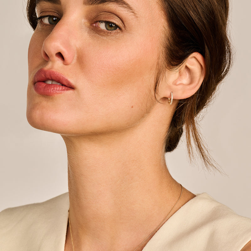 Oorring van 14k geelgoud met kleine zirkonia aan oorlel, bicolor goud uitstraling.