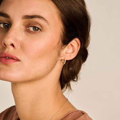 Oorring van 14k geelgoud met kleine zirkonia in minimalistische stijl.