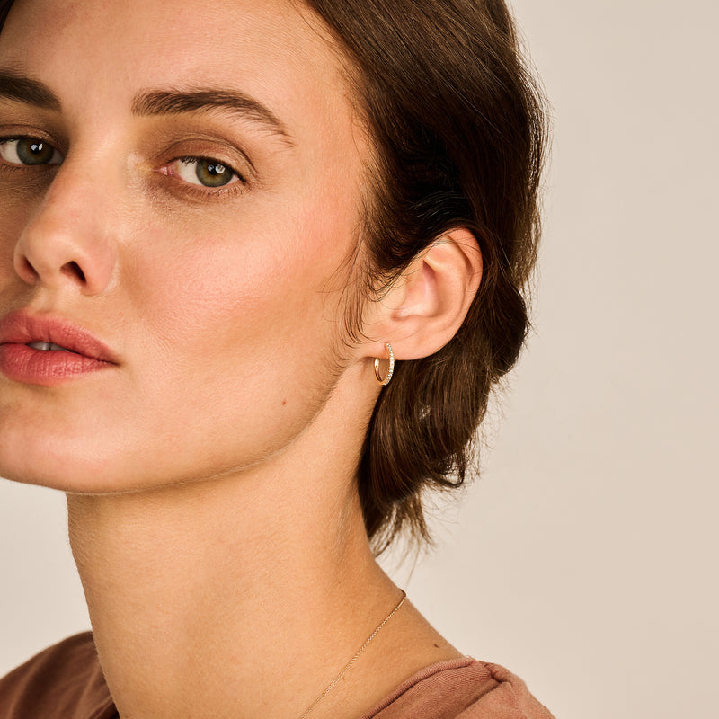 Oorring van 14k geelgoud met kleine zirkonia in minimalistische stijl.