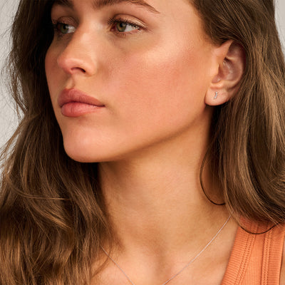 Oorknopjes in 14k wit goud met sprankelende zirkonia aan oor van vrouw.