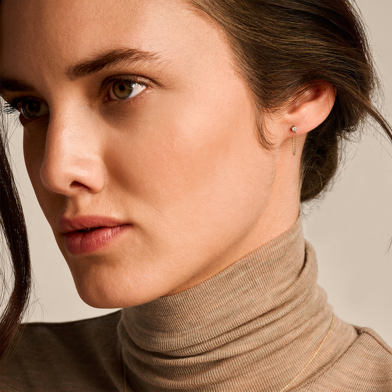 Oorknopje van 14k geelgoud met kleine sprankelende zirkonia in het oor gedragen.