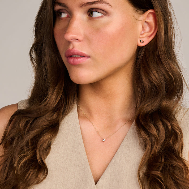 14k geelgouden ketting met kleine zirkonia hanger gedragen door vrouw.