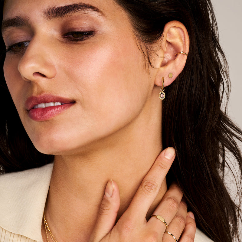 14k rosé goud oorring met zirkonia aan linker oor met subtiel design.