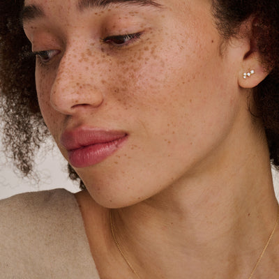 Oorstekers van 14k wit goud met kleine zirkonia in oor van vrouw.