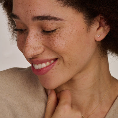 vrouw met 14k gouden oorknopjes in V vorm