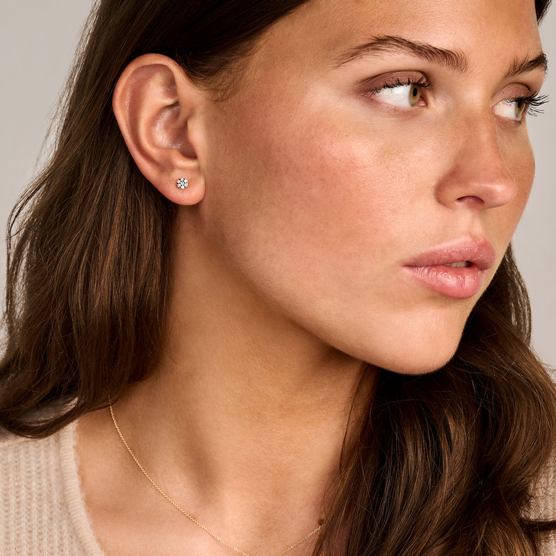 Bicolor oorknoppen met natuurlijke diamant in 14k geel en wit goud, close-up oor zacht licht.