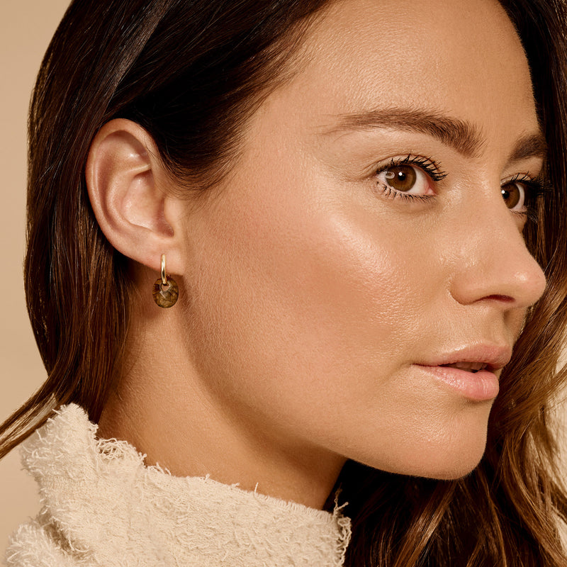 Oorbellen met labradoriet bedel en 14k rosé goud bevestiging aan vrouwenoor.