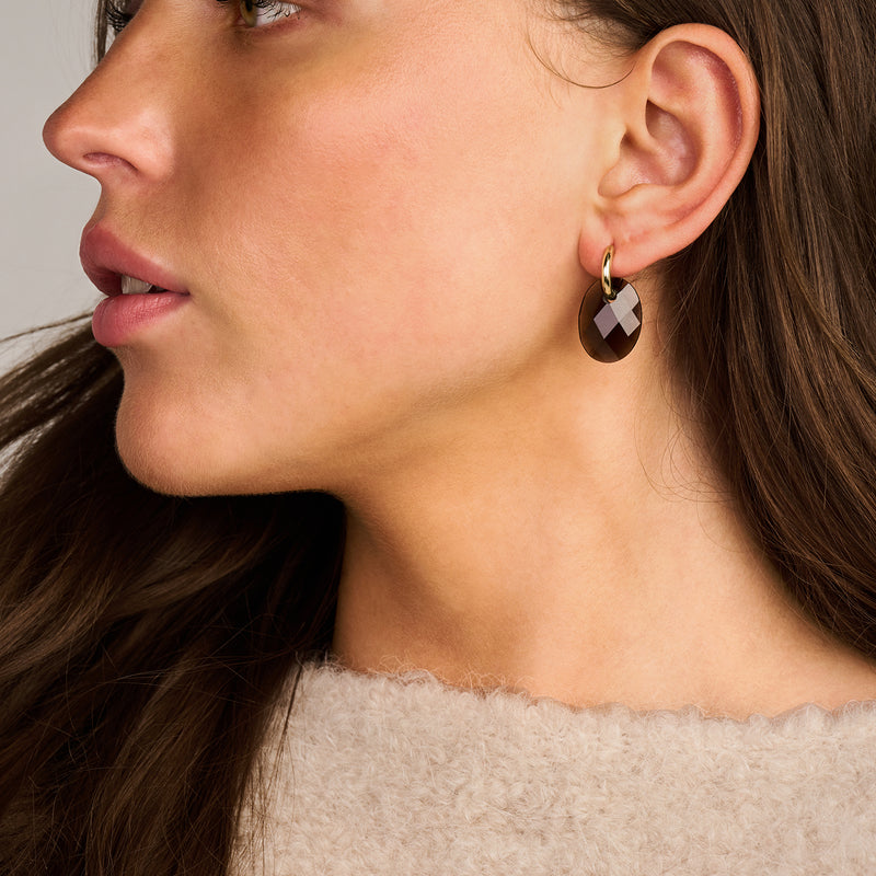 Oorbellen met rookkwarts hanger in 14k goud aan oorlel.