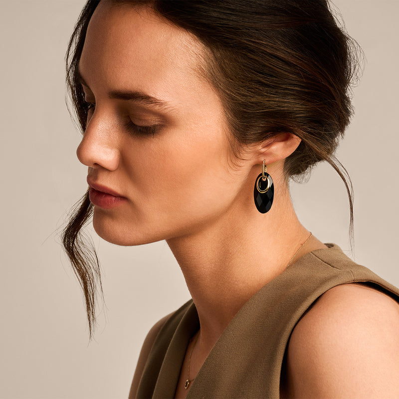 Oorbellen met zwarte onyx hangers en 14k Goud afwerking, gedragen door een vrouw.
