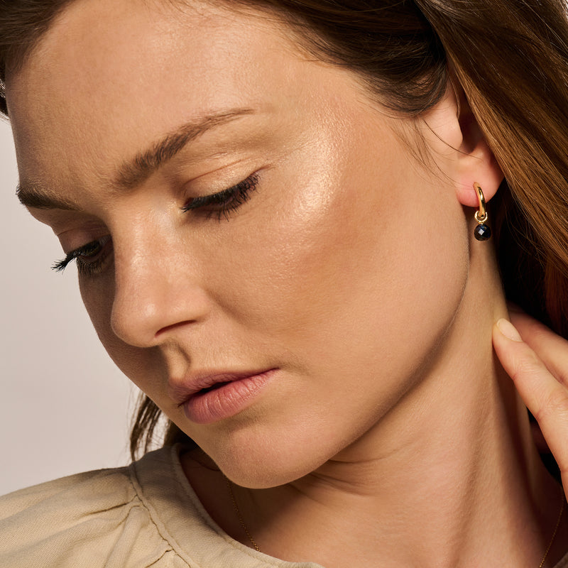 14k geelgouden oorbellen met kleine zirkonia en zwarte accentstenen.