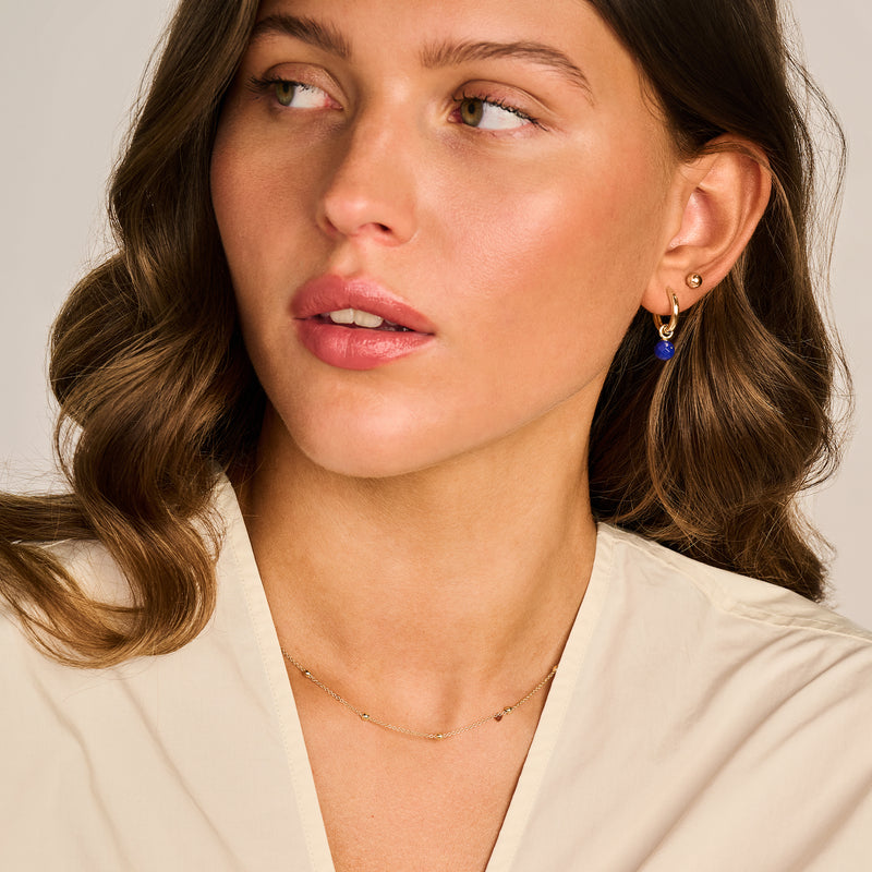 Oorbedels van 14k geelgoud met blauwe lapis lazuli steen, subtiel design.