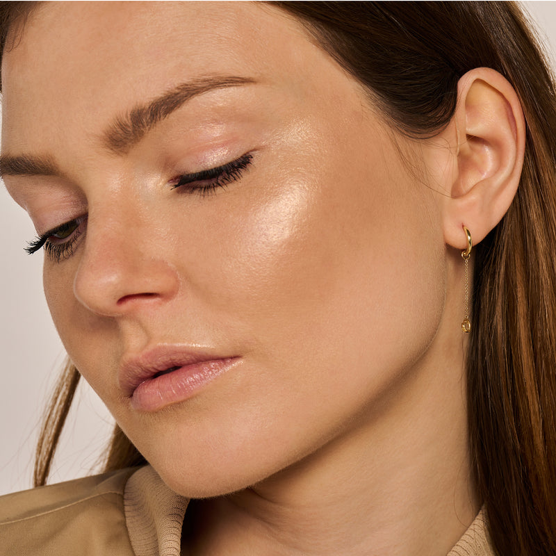 Fijne 14k geelgouden oorbel met subtiele schakel en glinstering aan model.