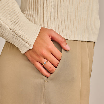 Solitair ring met Lab Diamond in 14k geel goud op hand in beige outfit.