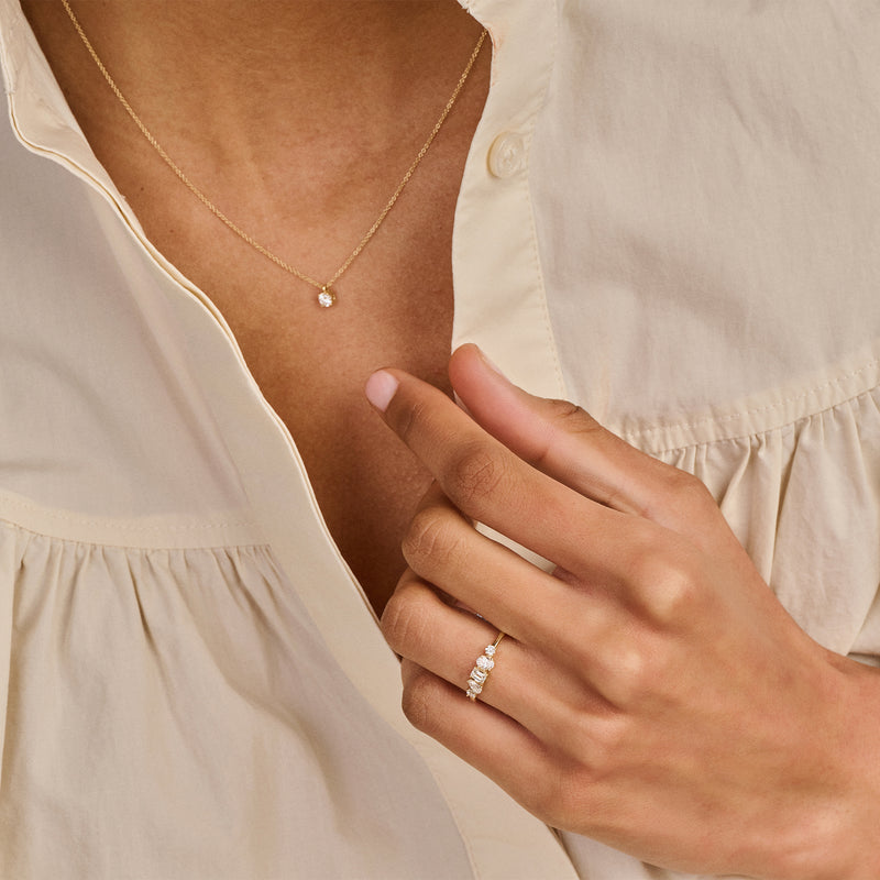 14k goud collier met fijne schakel en kleine lab diamant hanger op huidkleurige blouse.