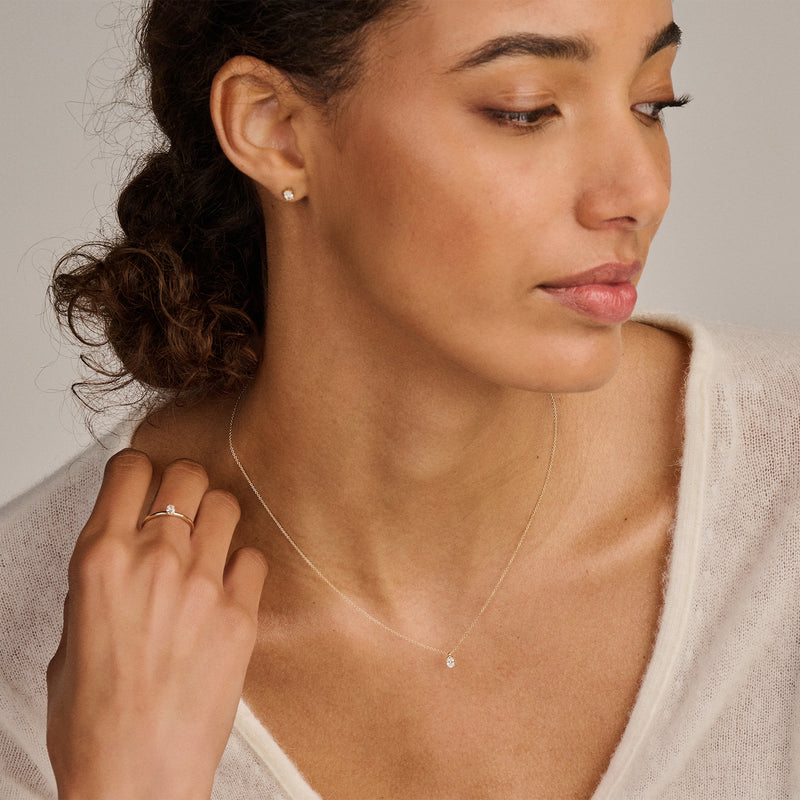 Dunne 14k Goud solitair ring met kleine lab diamanten op vrouwelijke hand.