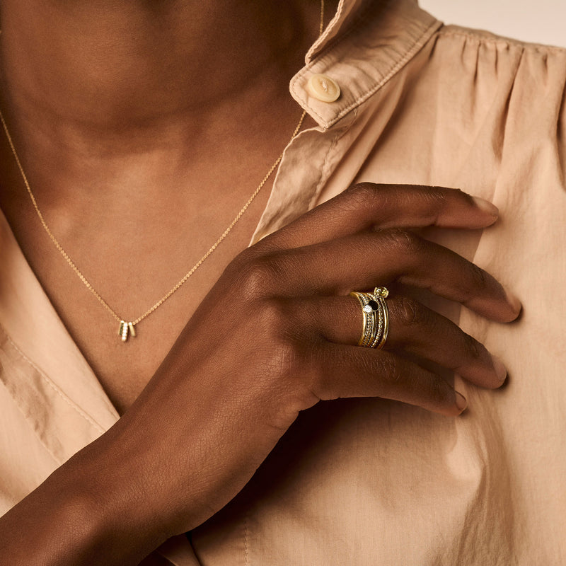 Stapeling van drie fijne ringen in 14k geel goud met groene peridoot op middenvinger.