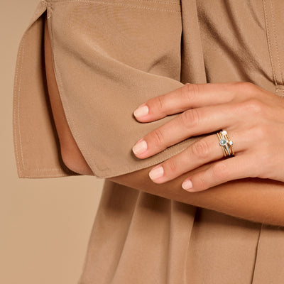 Bicolor gouden ring met blauwe topaas in 14k goud, gedragen aan wijsvinger.