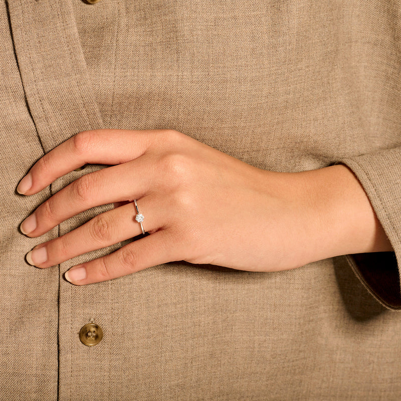 14k wit gouden ring met natuurlijke diamant op hand met beige linnen blouse.