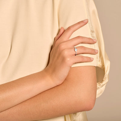 Diamanten ring 1655WDI in 14k wit goud met ronde diamant op vrouwelijke hand in beige blouse.