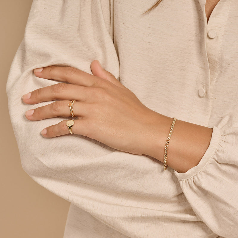 14k geelgouden fijne schakel armband subtiel om pols in naturel lichte blouse.