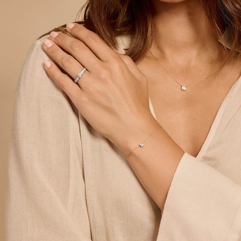 Bracelet fin en Or blanc 14k avec des petits Zircone sur le poignet d'une femme au top beige.