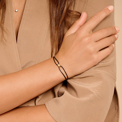 Bicolor goud armband met zwart zijdekoord en 14k geelgouden sluiting.