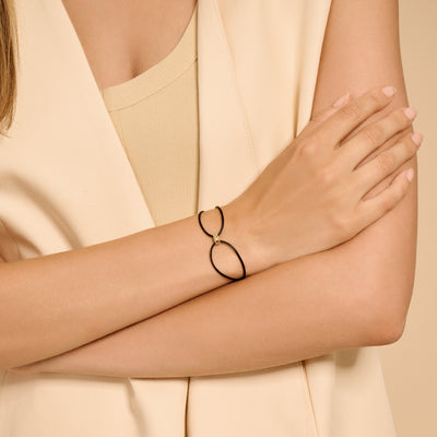 Bracelet bicolore en or avec deux maillons ovales reliés et cordon en soie noire.