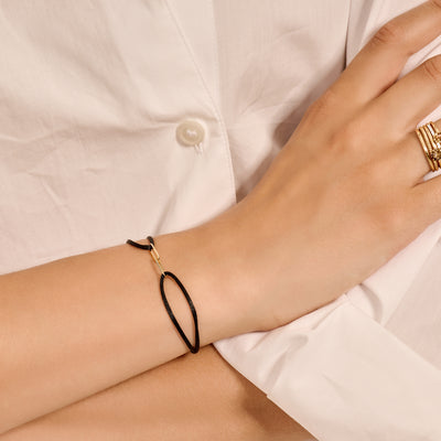 Armband met zwart zijdekoord en 14k geelgoud sluiting op pols.
