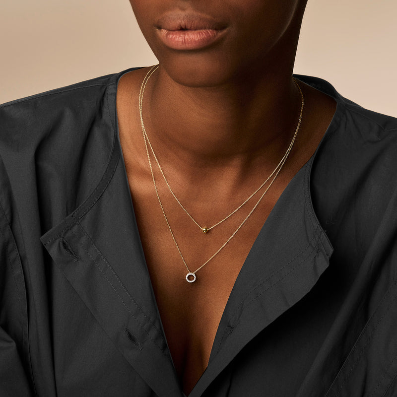 Dubbele ketting met fijne schakel en ronde hanger van 14k geelgoud.