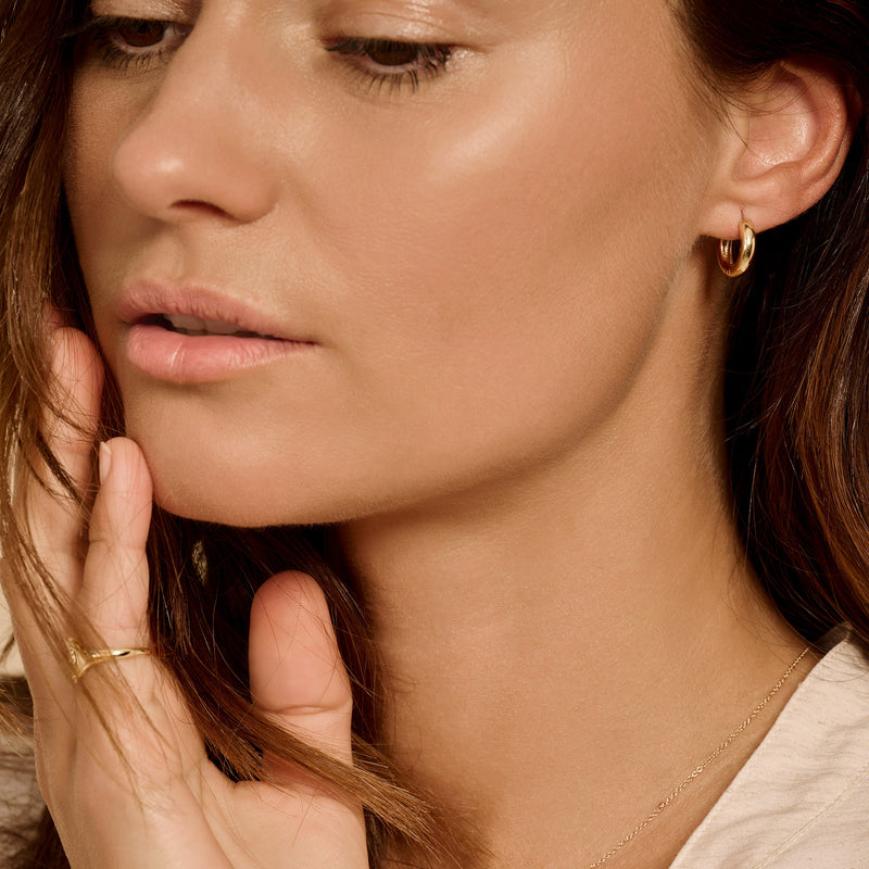 14k geelgouden oorringen met ronde vorm en glanzende afwerking .