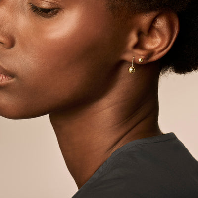 Oorknopjes van 14k geelgoud met ronde hanger aan oorlel.