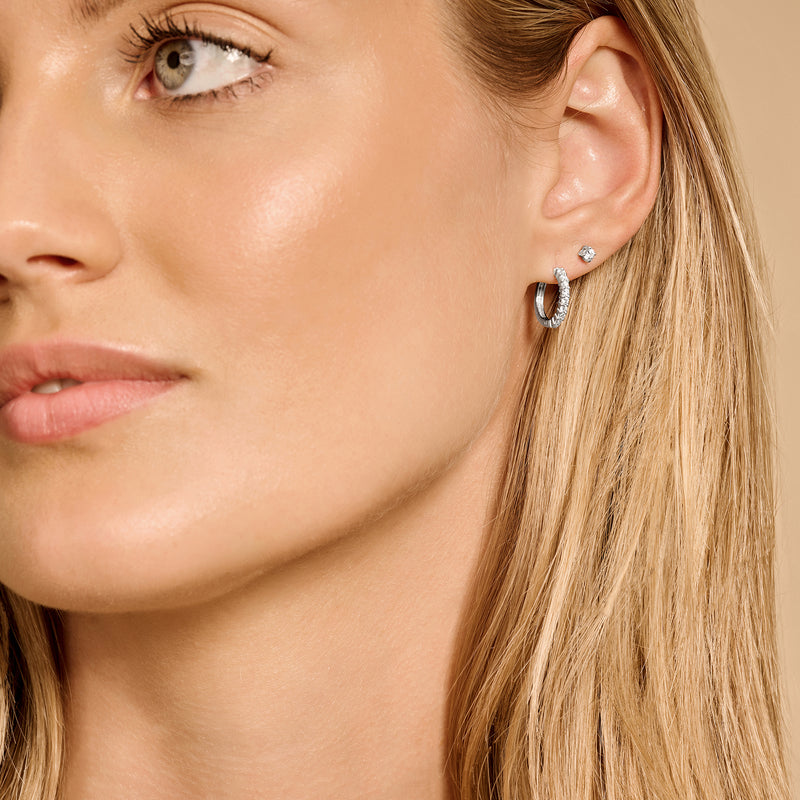 Oorknop van 14k wit goud met fonkelende zirkonia steentje aan vrouwenoor.