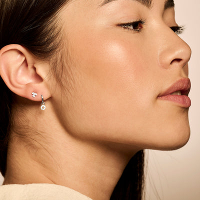 Oorringen 14k wit goud met kleine hanger en glanzende afwerking, bicolor goud details zichtbaar.