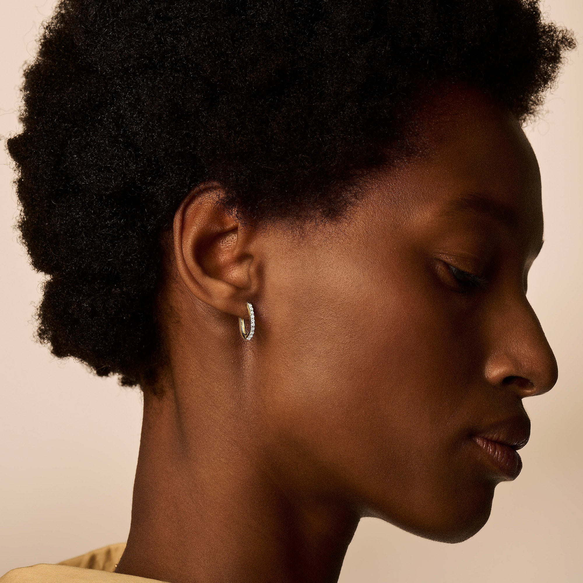 Oorring in 14k goud met subtiele zirkonia details, close-up profielzicht.