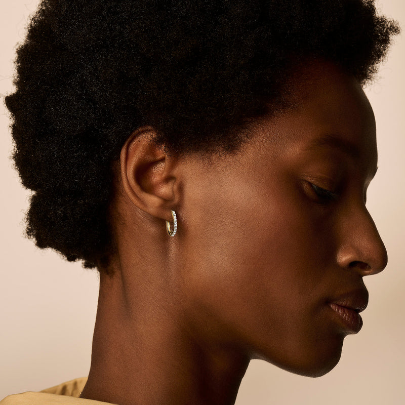 Oorring in 14k goud met subtiele zirkonia details, close-up profielzicht.