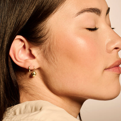 Oorbellen in 14k geelgoud met bolvormige hanger, subtiel glanzend oppervlak.