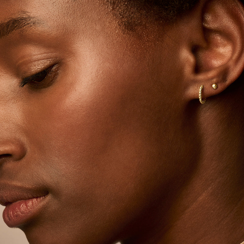 Oorring van 14k geelgoud met fijne gedraaide details aan oorlel.