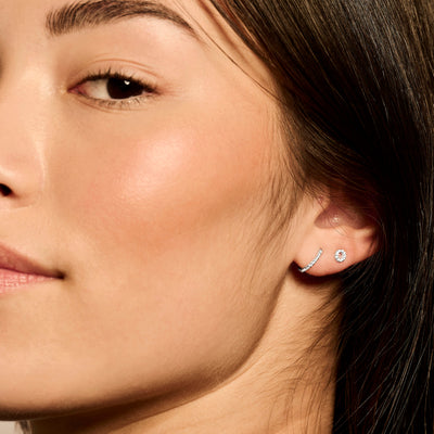 Oorring in 14k wit goud met kleine heldere zirkonia steen close-up aan oor.