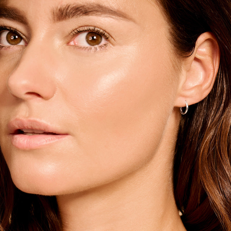 Kleine 14k witgouden oorringen subtiel gedragen aan oorlel.