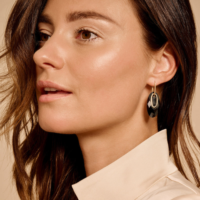 Oorringen met dubbele ovalen van 14k goud aan oor van vrouw.