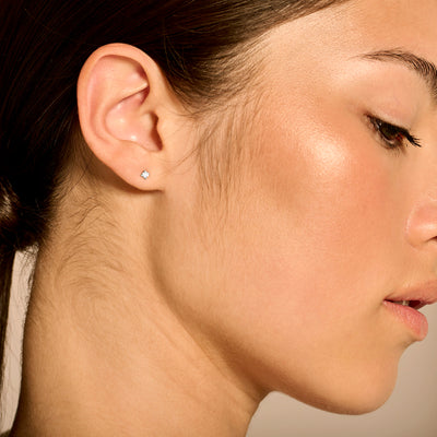 Wit gouden oorknopje van 14k goud met fonkelende natuurlijke diamant naast oorlel.