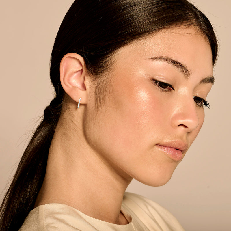 14k goud oorknopje met kleine diamant, minimalistisch design, close-up profielvrouw.