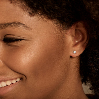 Oorknop van 14k wit goud met kleine ronde diamant in oor zichtbaar.