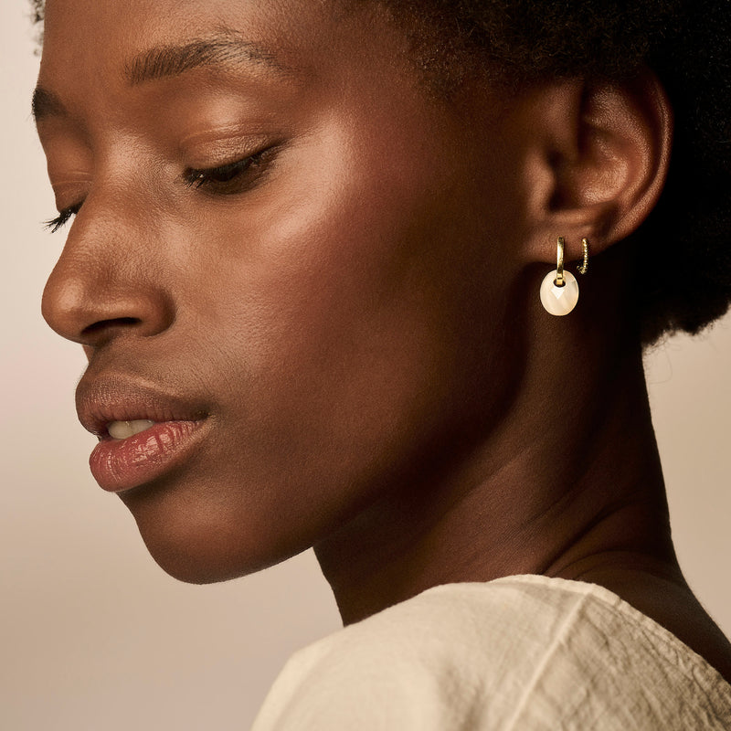 Ohrringe mit Perlmutt-Anhänger aus 585er Gelbgold am weiblichen Ohr.