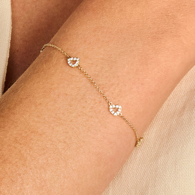 Fijne armband van 14k goud met twee hartvormige zirkonia schakels op de pols.