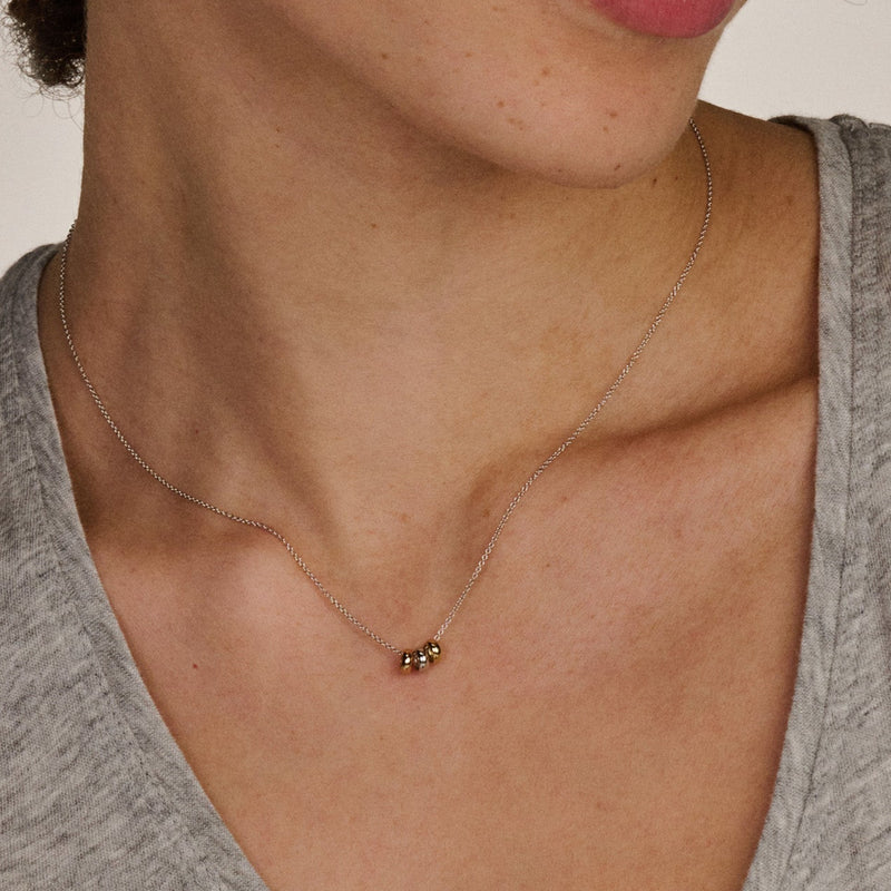 Delicate ketting met drie kleine ringetjes in bicolor 14k goud, subtiel en verfijnd.